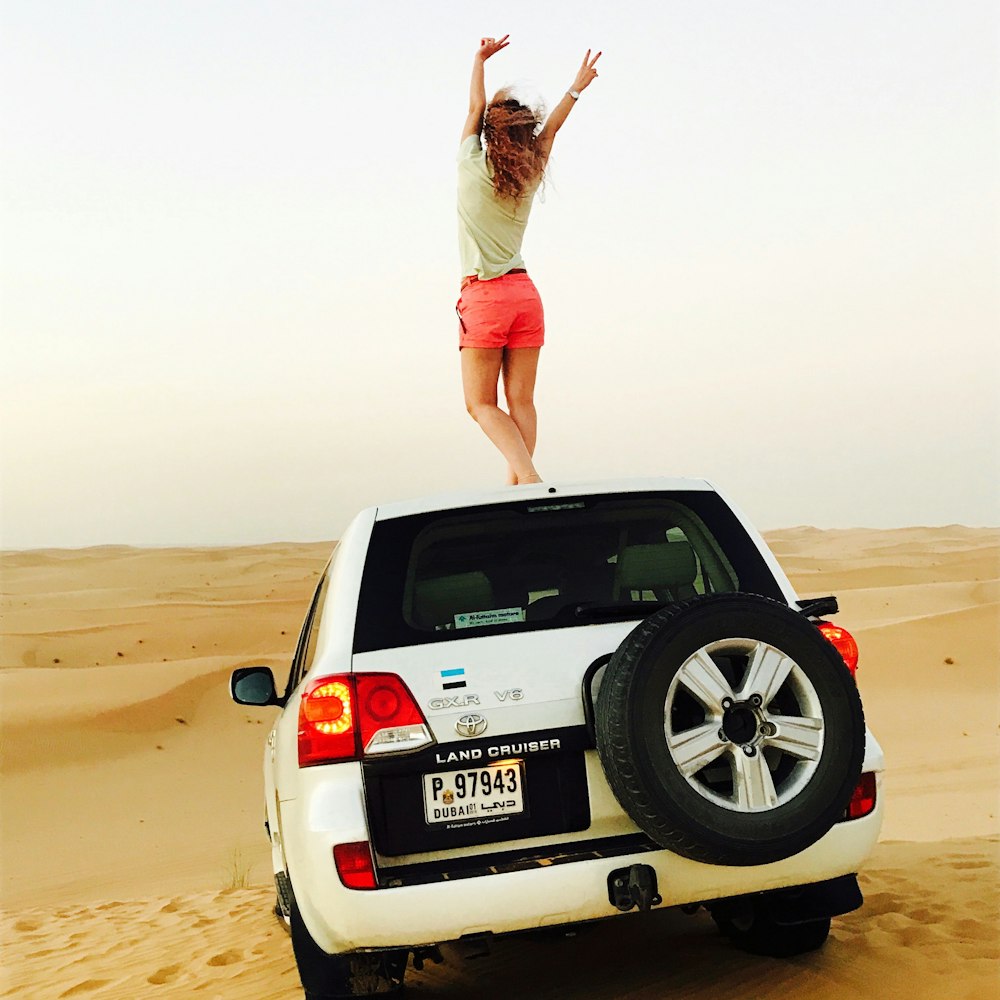 woman in white tank top and white shorts standing on brown sand during daytime