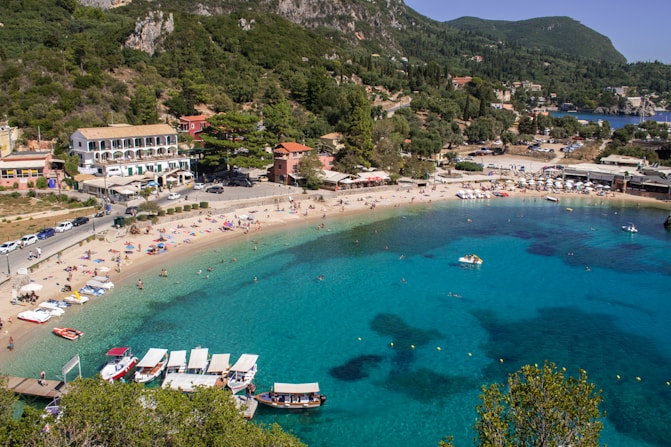 aerial view of boats on sea near green mountain during daytime