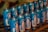 Multiple blue cans featuring images and text in an organized display, possibly representing a religious or spiritual theme. The design on the cans includes a depiction of a figure resembling religious icons, and the text is in a foreign language, suggesting a cultural context.
