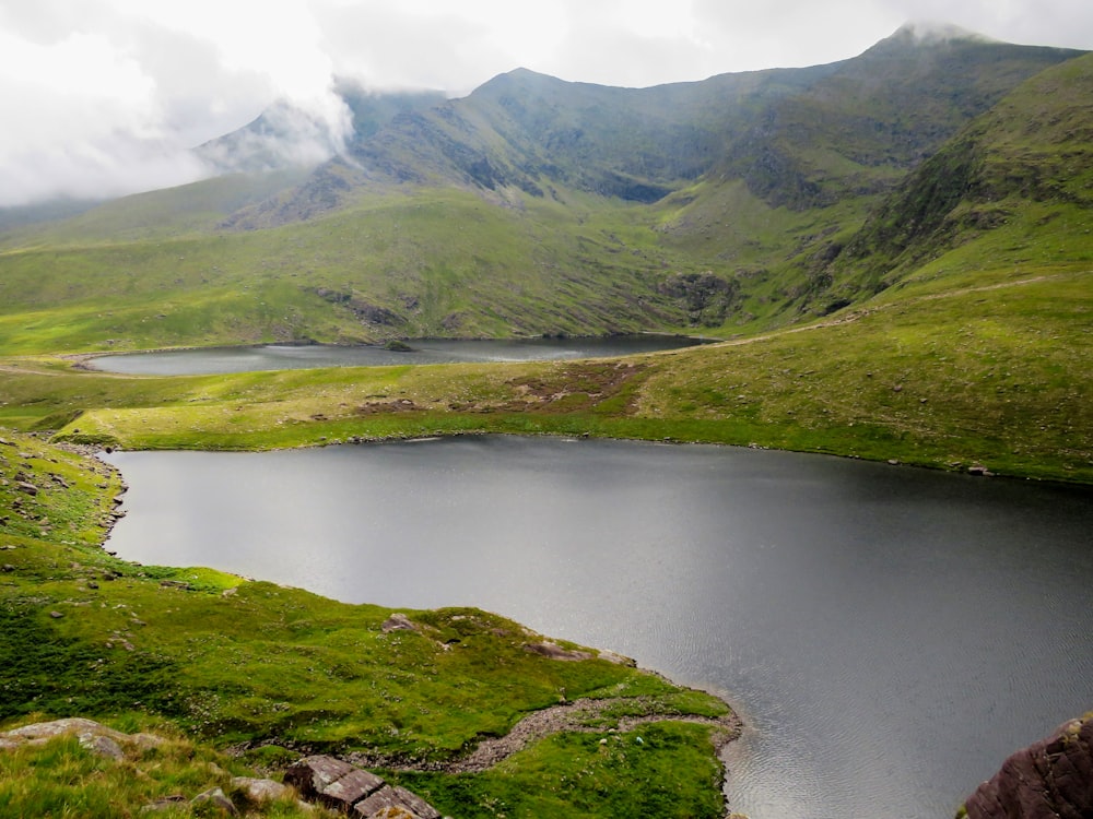 green and brown mountain beside lake during daytime