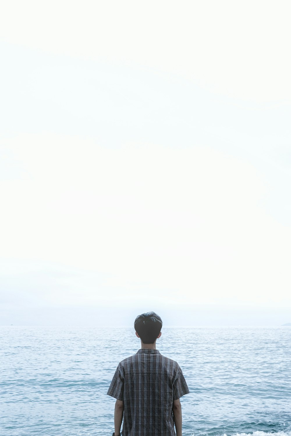 man in black shirt standing on sea during daytime