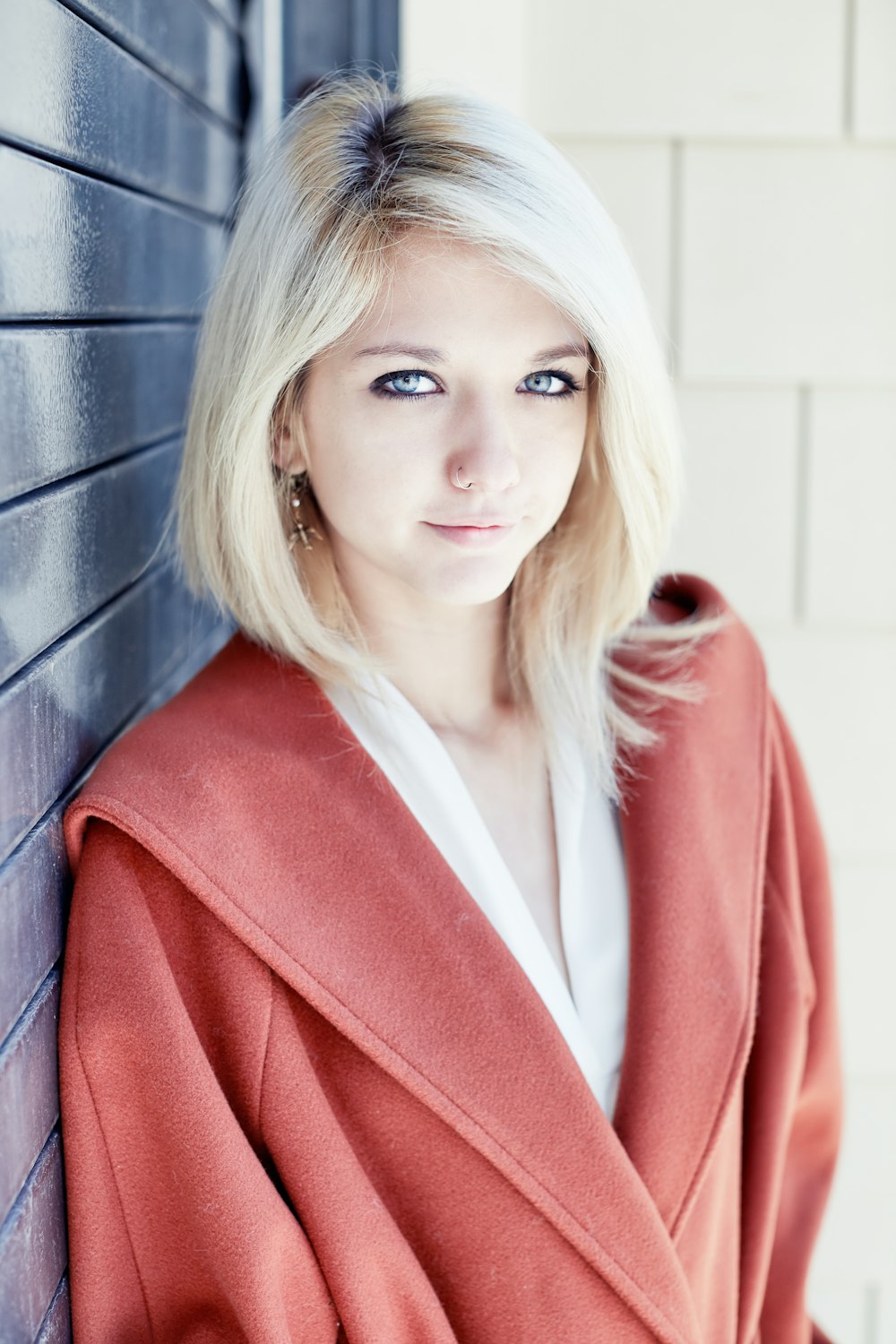 woman in red blazer standing beside black wall