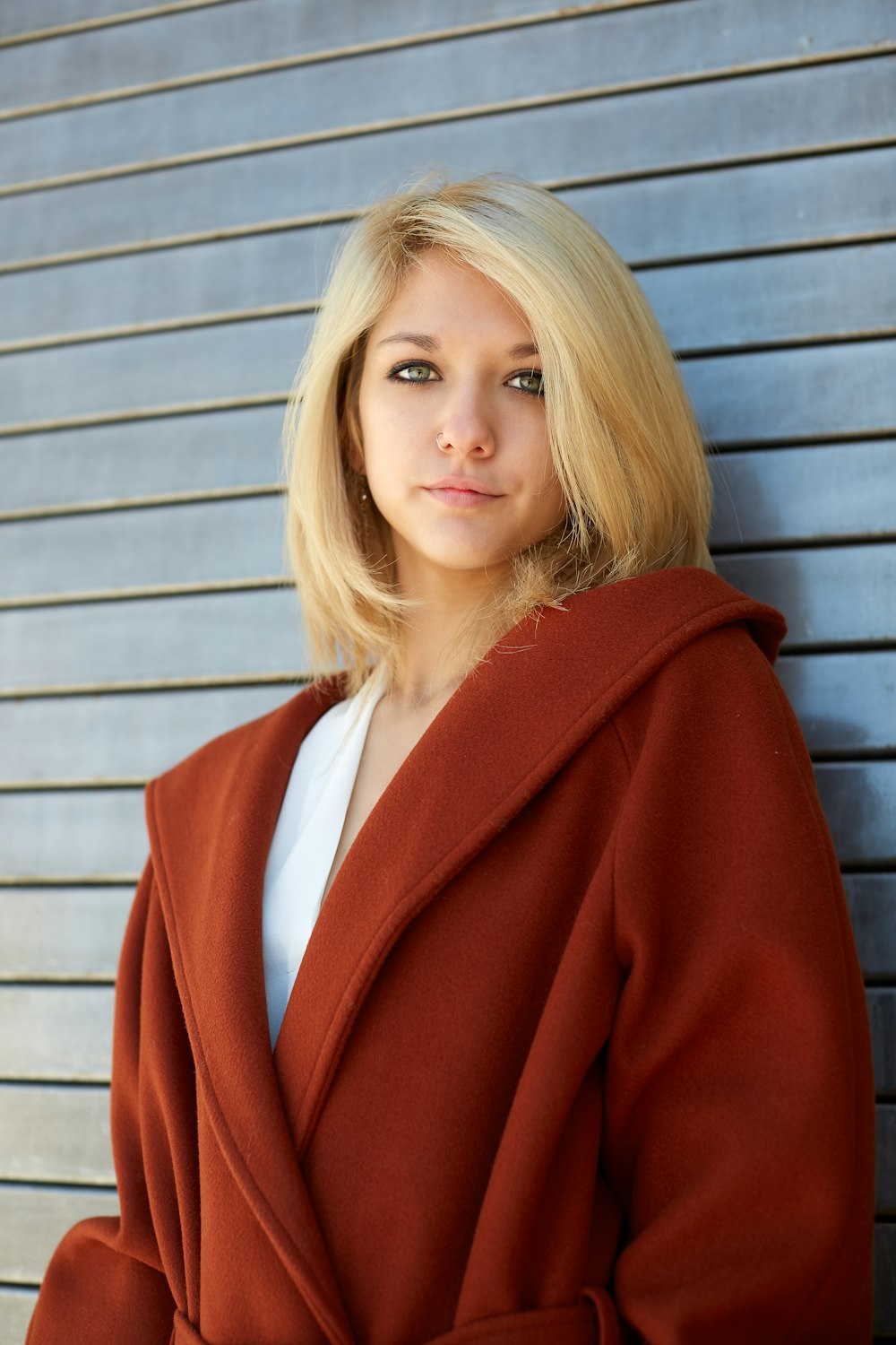 woman in red blazer standing near brown wooden wall