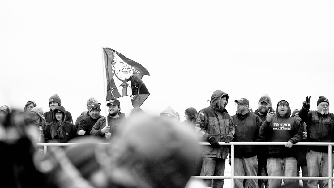 grayscale photo of man holding flag, Trump Rally + Counter Protest.