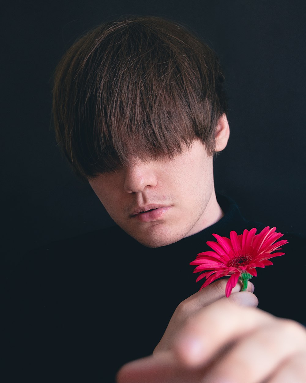 man holding red flower in black background