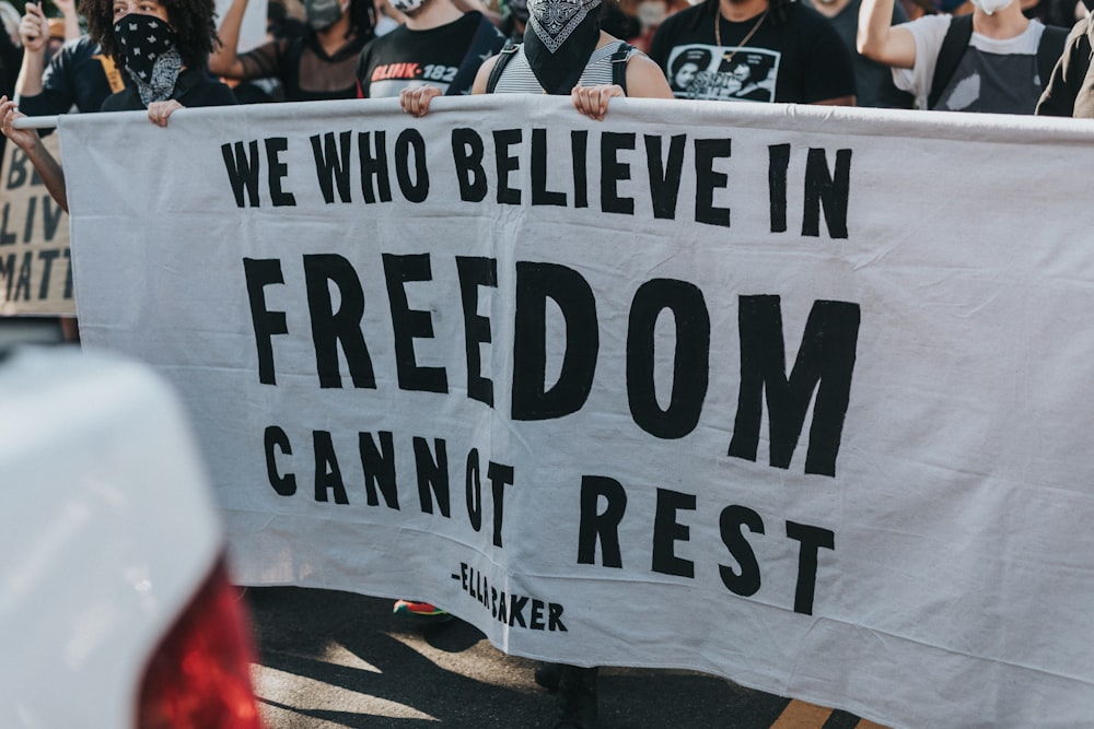 Eine Gruppe von Menschen, die ein Schild halten, auf dem steht, dass wir, die wir an die Freiheit glauben, "