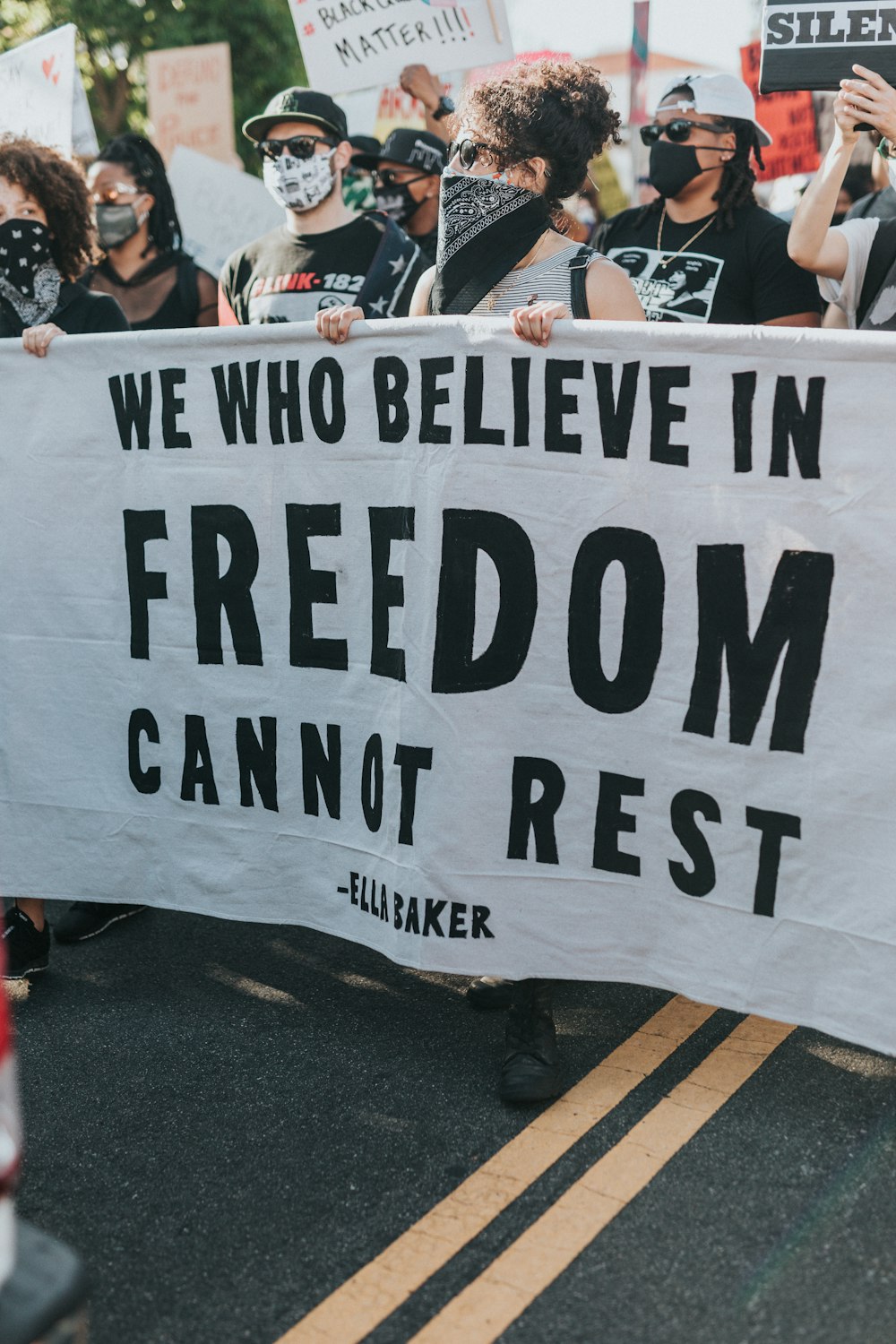 Un groupe de manifestants tenant une pancarte qui dit que nous qui croyons en la liberté ne pouvons pas nous reposer