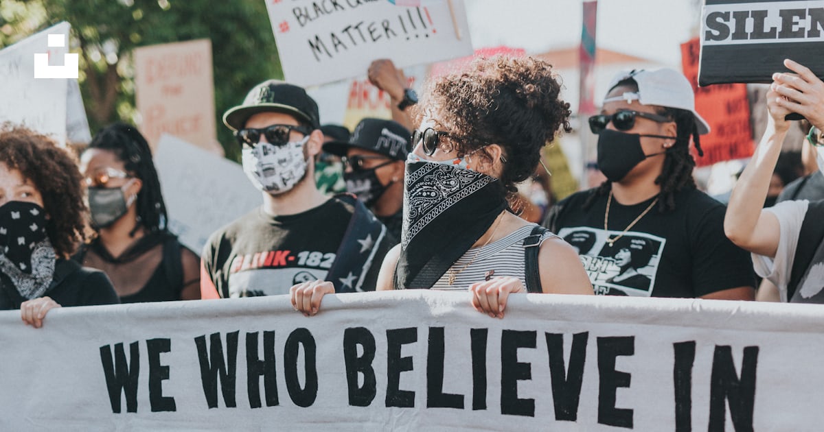 A group of protesters holding a sign that says we who believe in ...