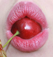 Close-up of a hand wearing smeared red lipstick holding a cherry-shaped candy with a neon pink backdrop.