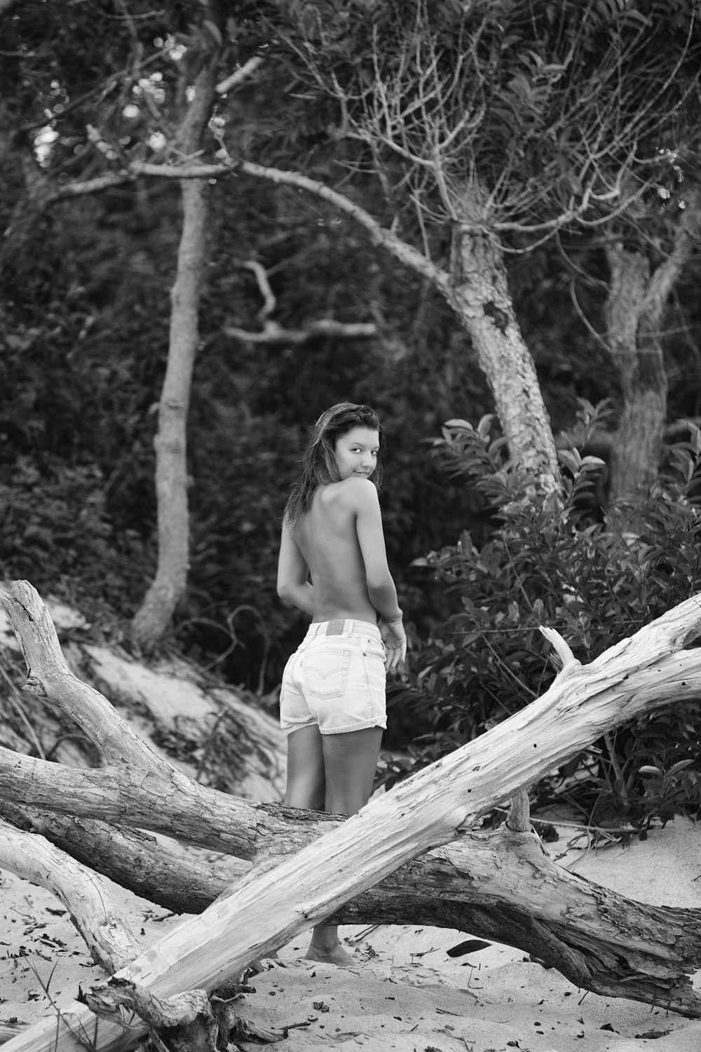 woman in white shorts standing on tree log in grayscale photography