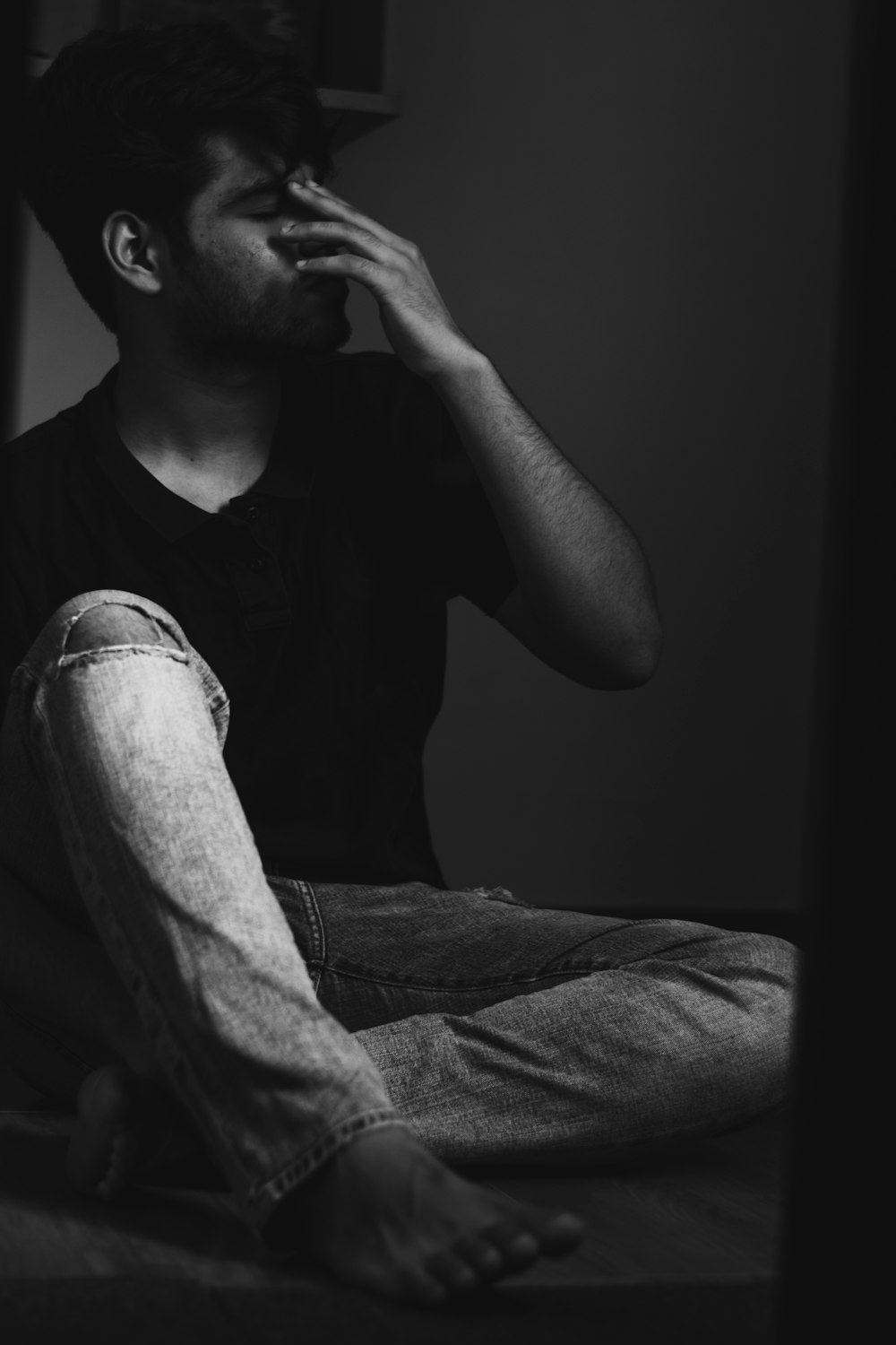 man in black crew neck t-shirt and denim jeans sitting on bed