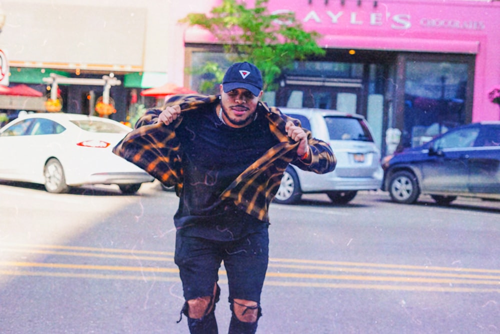 man in black and brown jacket and black pants standing on pedestrian lane during daytime