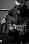 Monochrome portrait of a musician deeply focused while playing an acoustic guitar.