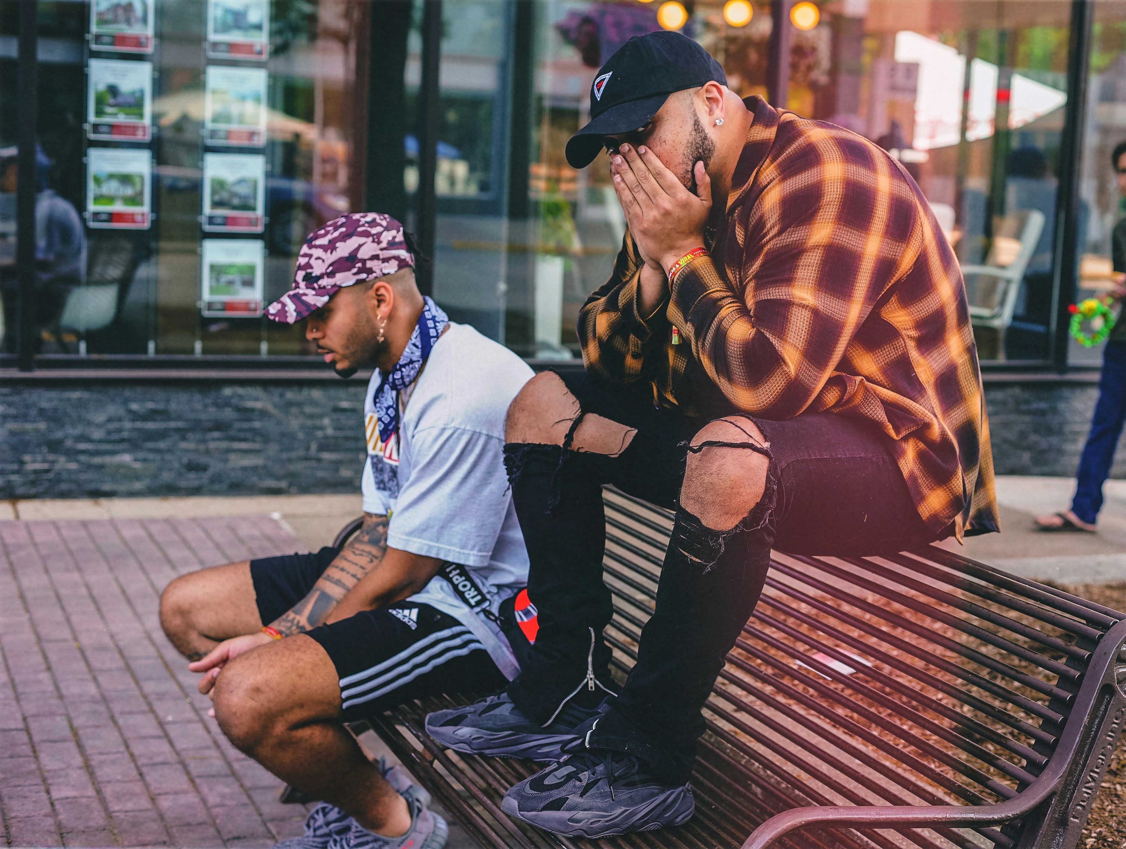 Homme en pull rayé orange et blanc assis sur un banc en bois marron