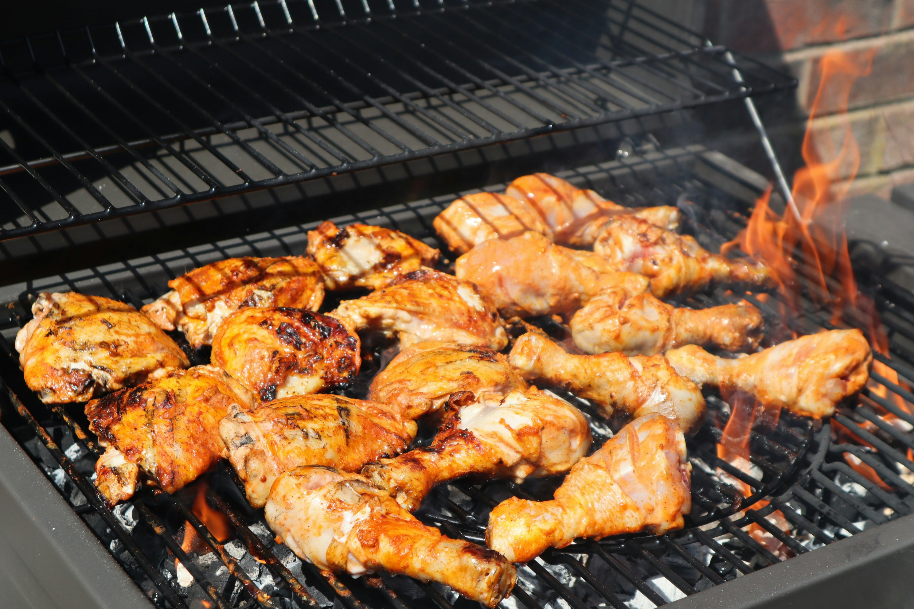 BBQ chicken pieces on grill with char marks and smoke