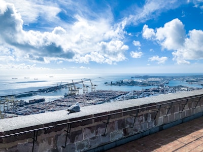 A panoramic view of a bustling international port with containers and cranes under a clear sky.