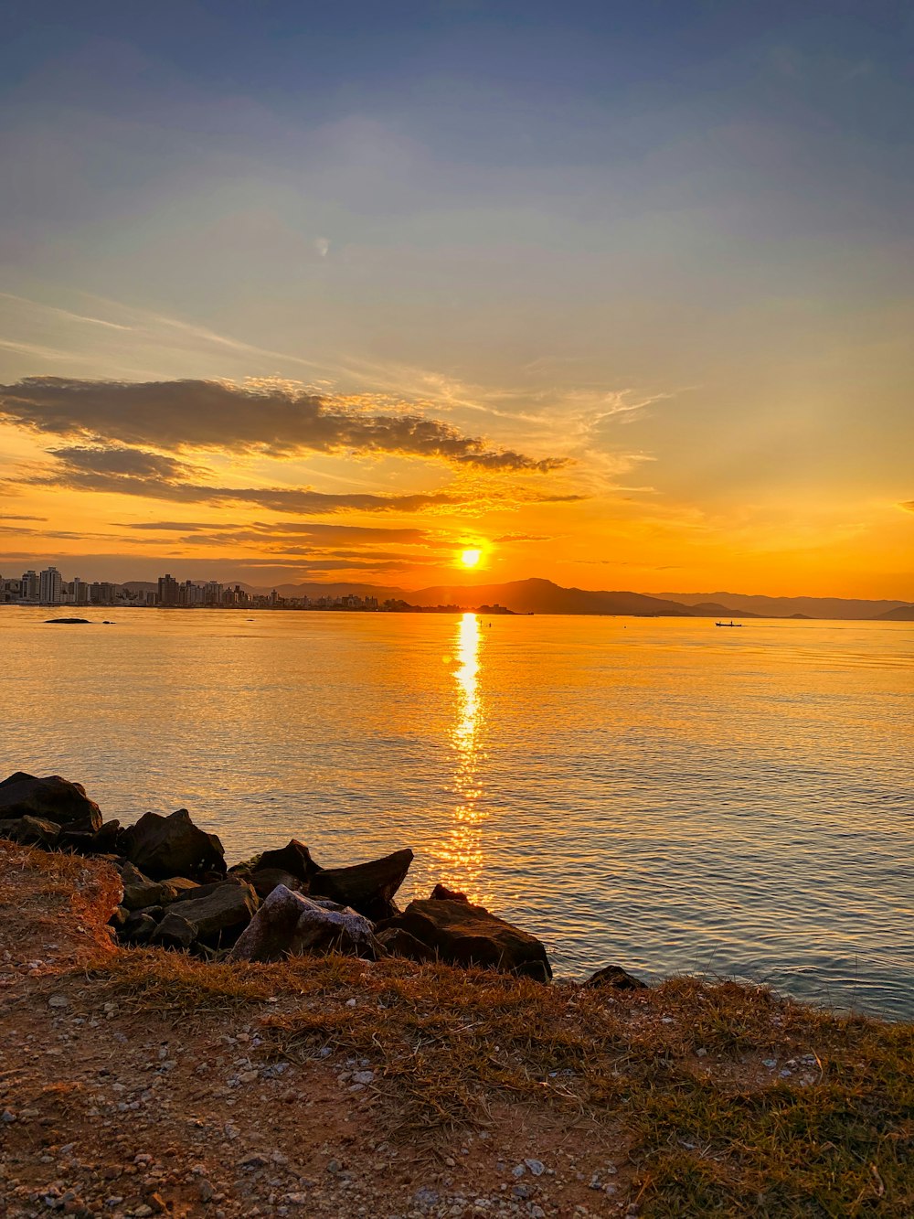 silhouette of rocks on sea shore during sunset