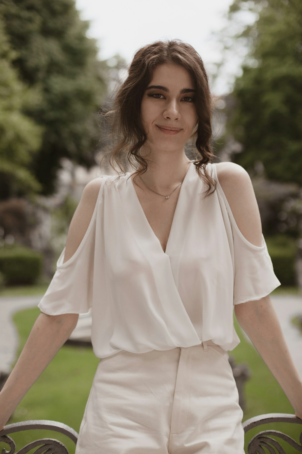 Femme en chemise blanche à col en V debout sur le champ d’herbe verte pendant la journée