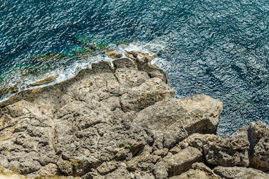 brown rock formation beside blue sea during daytime in Rhodes Greece