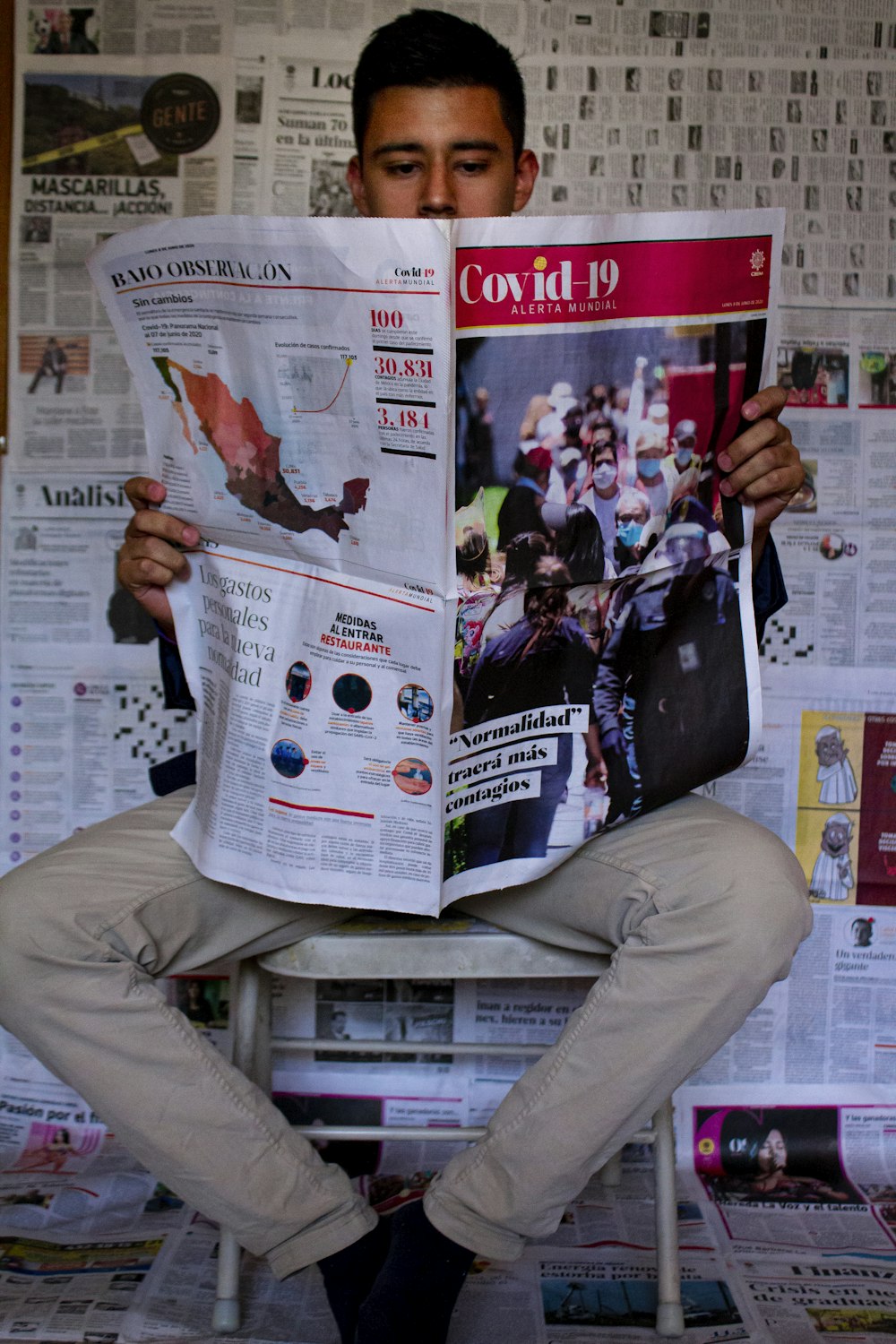 man in black leather jacket and gray pants holding newspaper