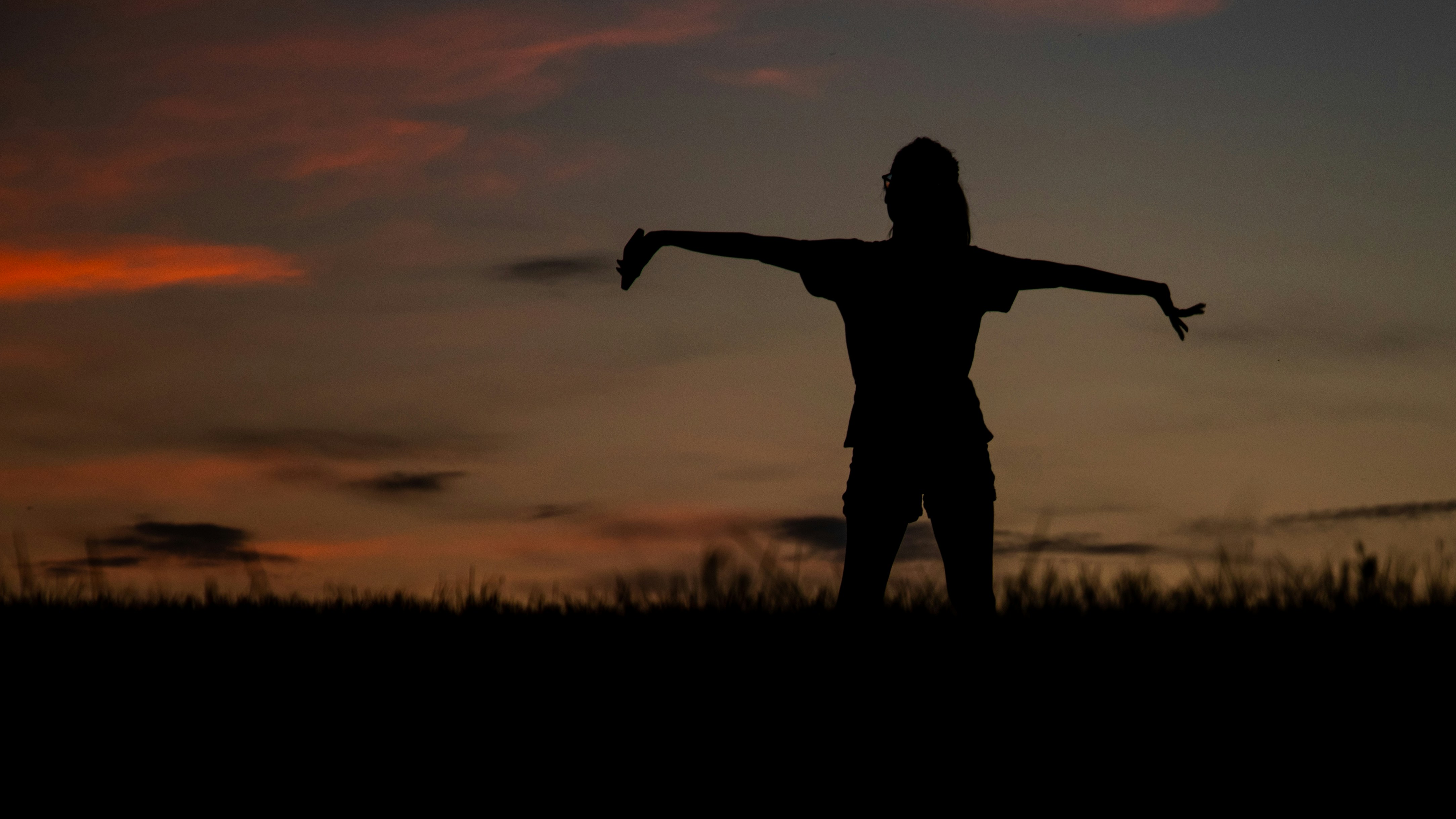 silhouette of man standing on grass field during sunset
