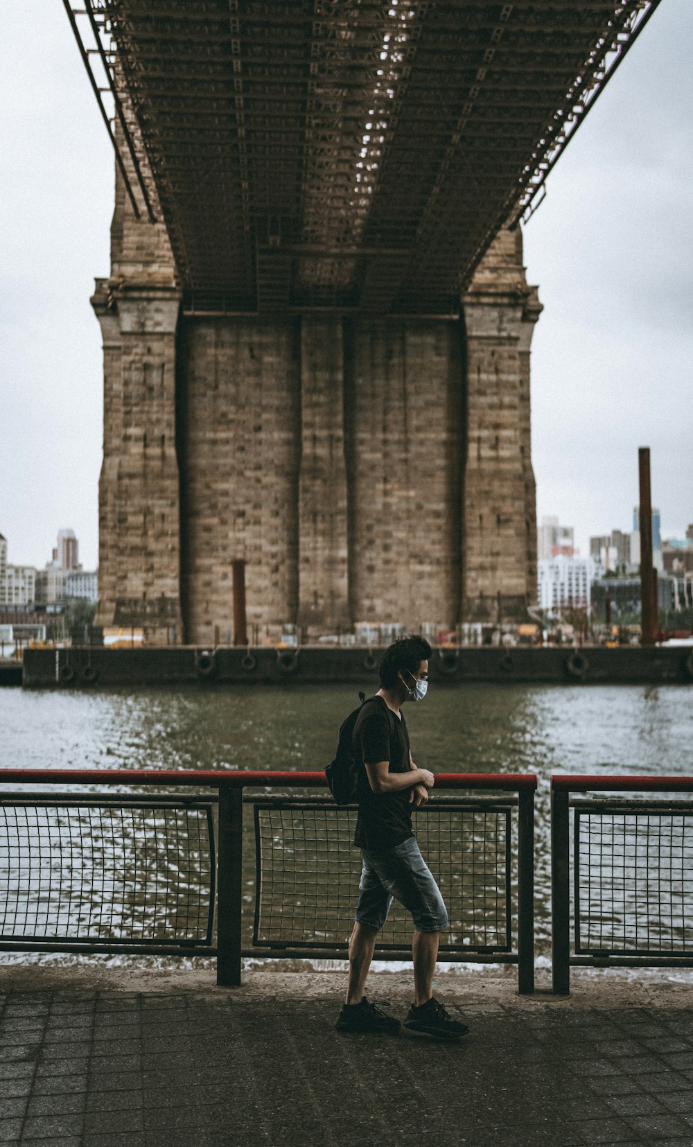 man in black jacket and blue denim jeans standing near brown concrete building during daytime