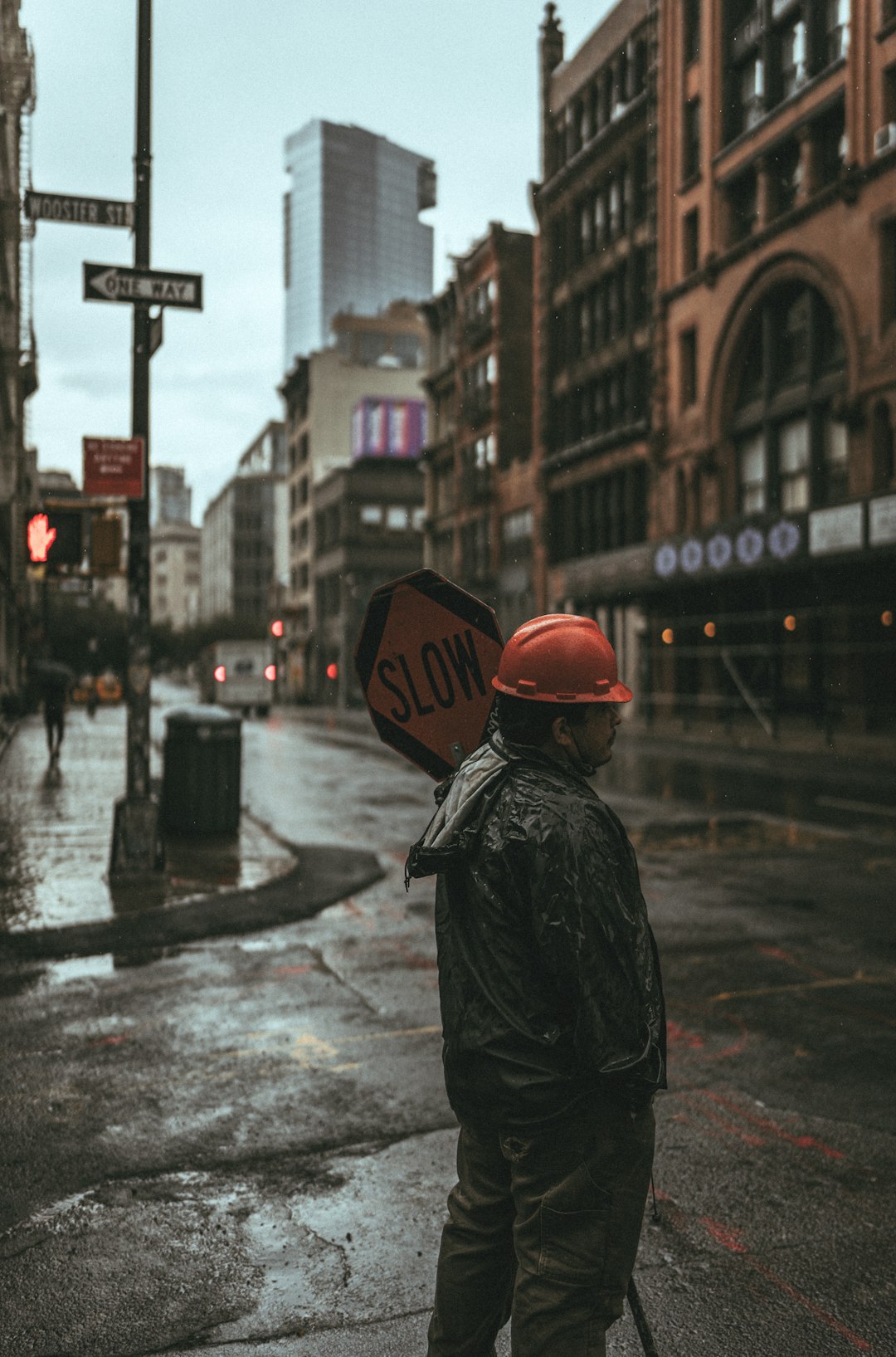 person in black jacket wearing orange helmet standing on road during daytime