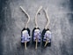 Three dark labels with strings are arranged side by side on a textured surface. Each label features a small bouquet of purple and white flowers attached to it.