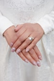 Close-up of delicate bridal nails with soft pink hues and subtle rhinestones.
