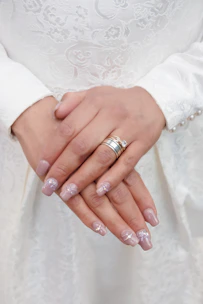 Bridal-inspired stiletto nails adorned with delicate diamond accents on a white surface.