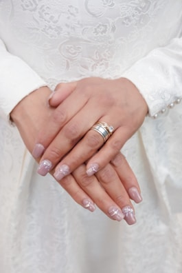 Close-up of delicate bridal nails with soft pink hues and subtle rhinestones.