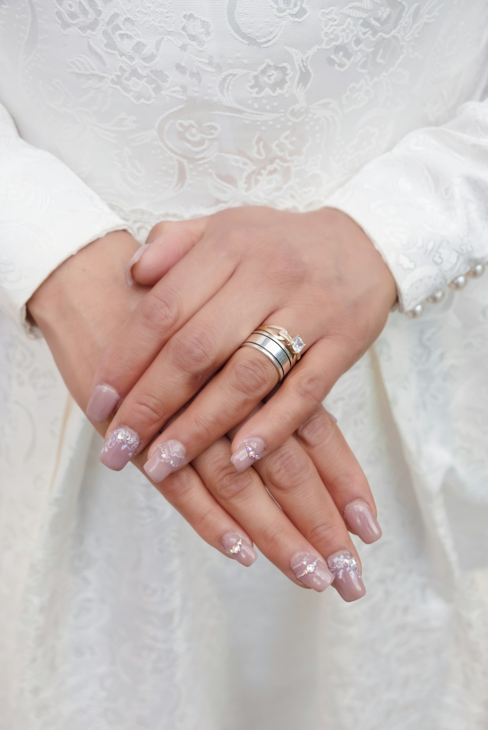 mujer con anillo de plata y vestido de encaje floral blanco