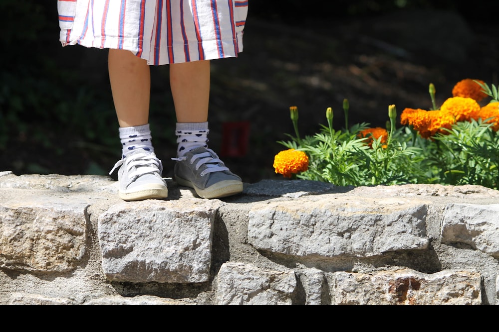 person in white sneakers standing on gray concrete blocks