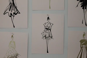 A designer sketching elegant women's fashion models in a bright studio.