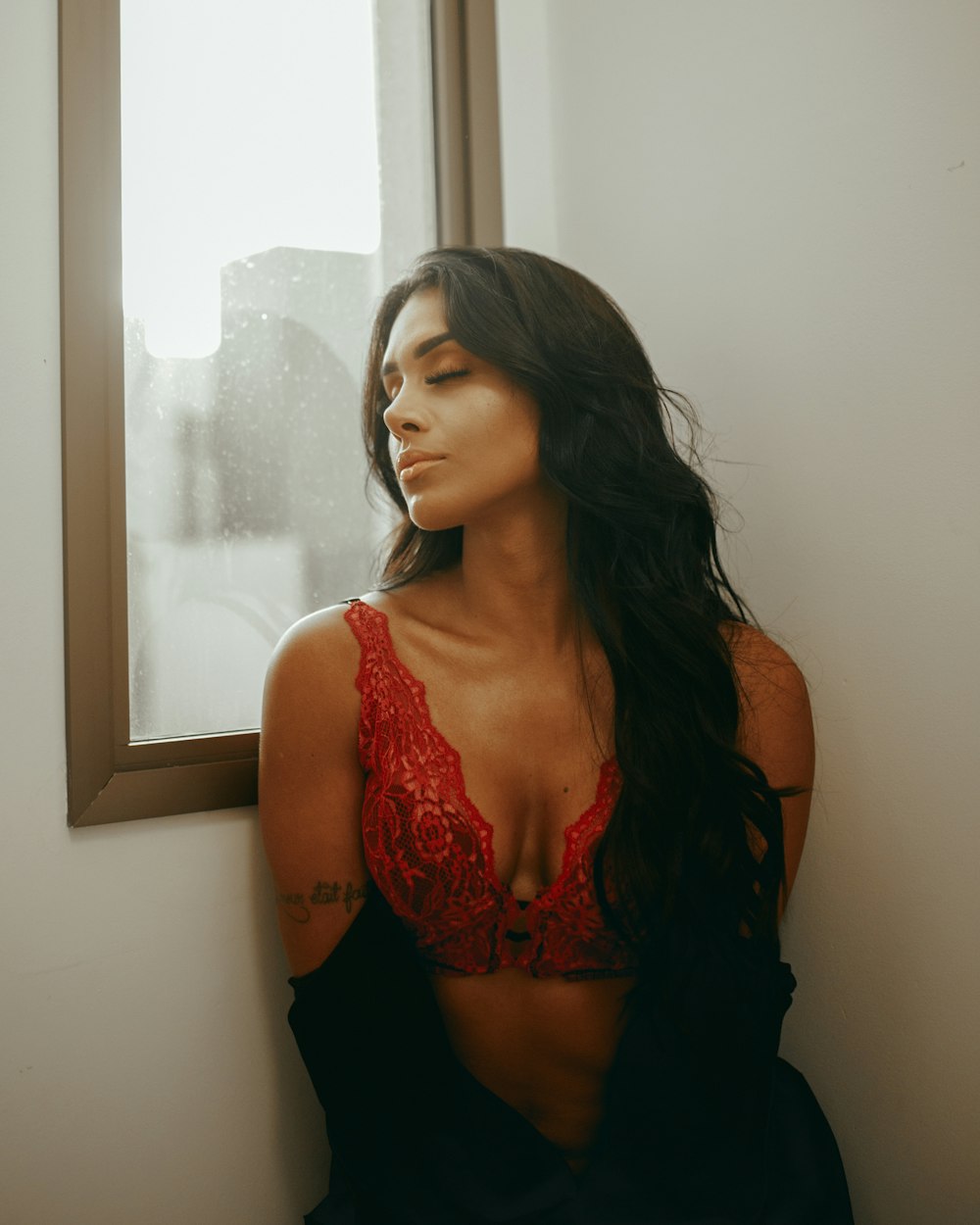 woman in red and black bra standing near window