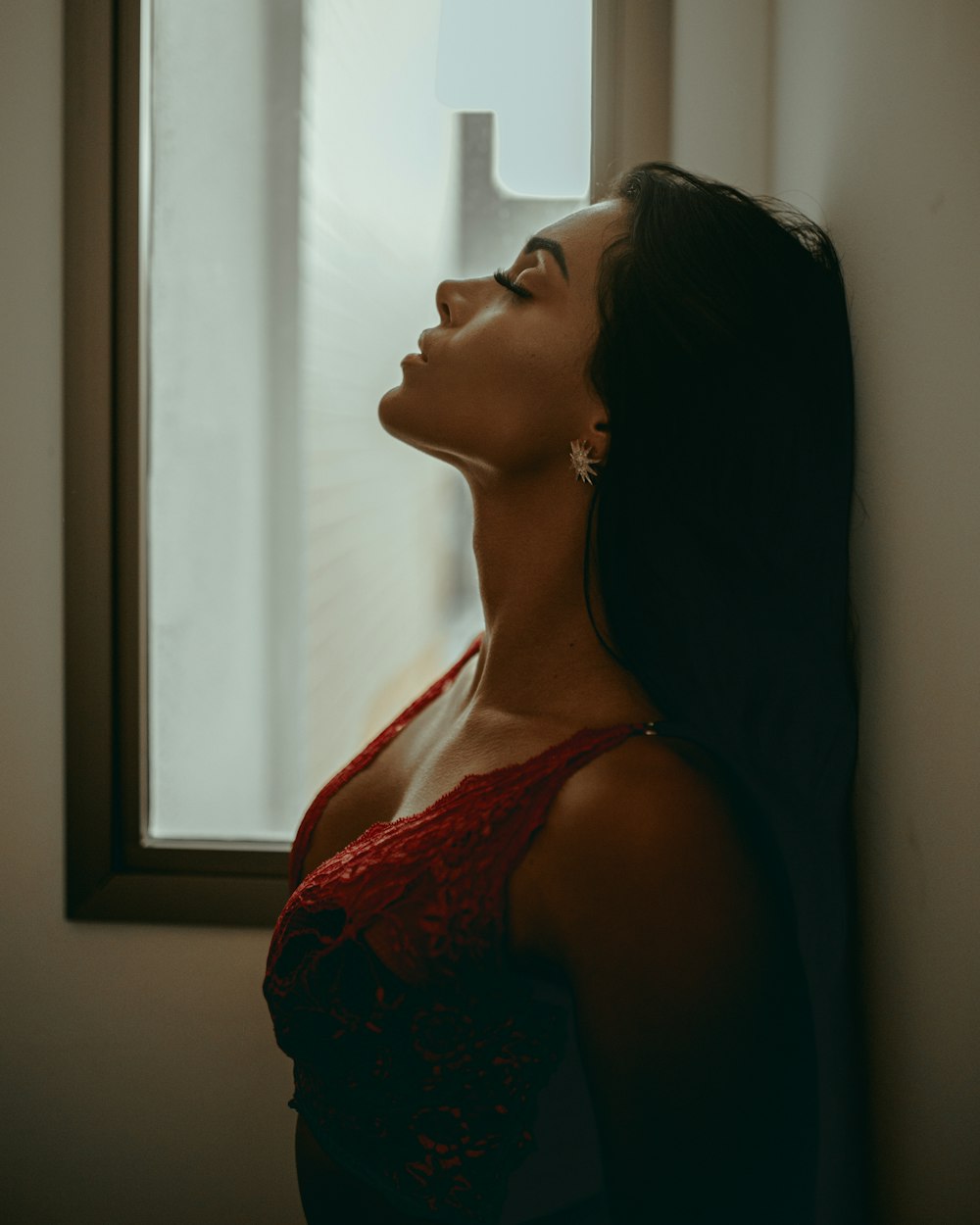 donna in top rosso con spalline sottili floreali che guarda la finestra