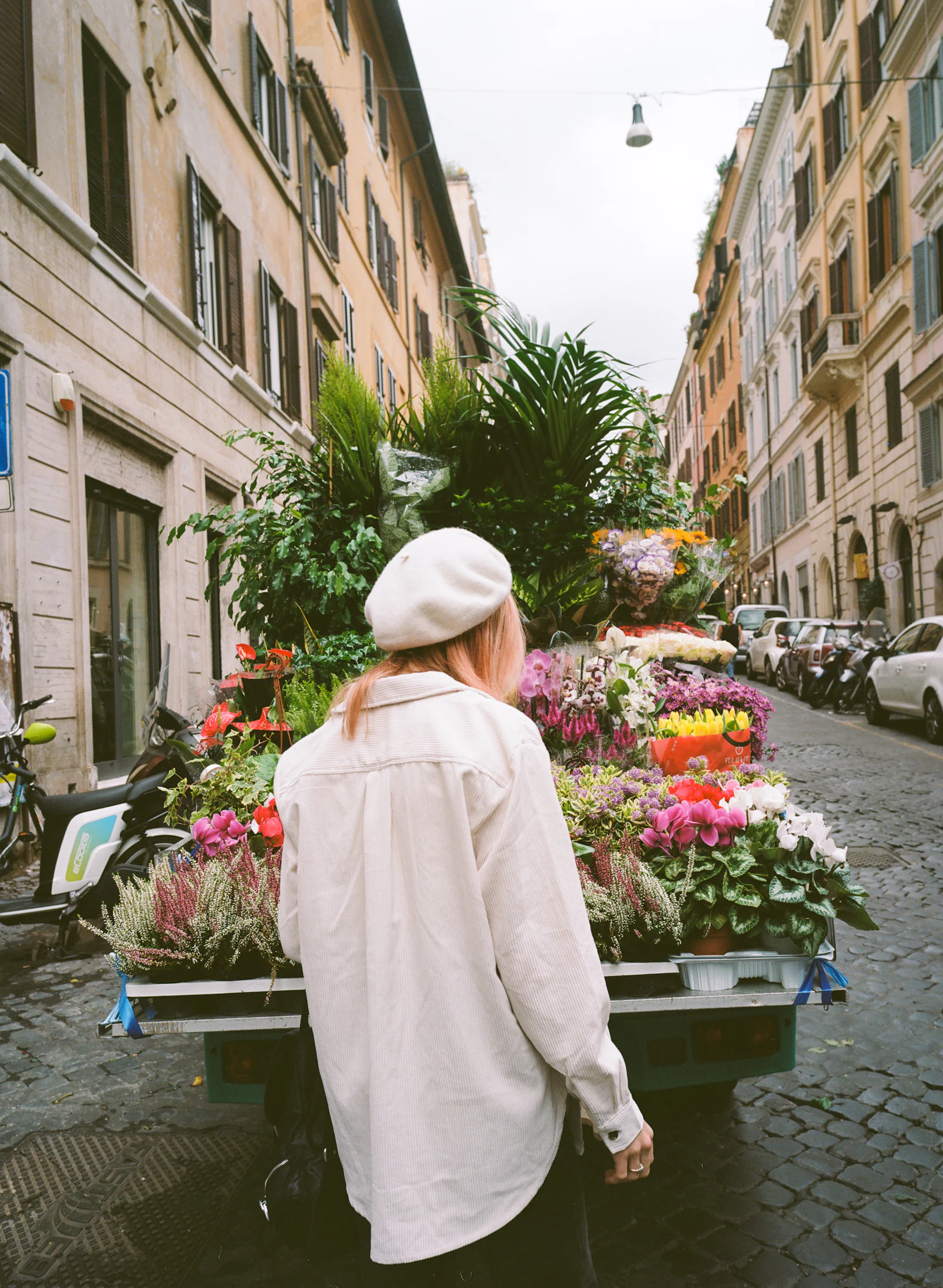 Femme en manteau beige et chapeau blanc dans une rue de Rome