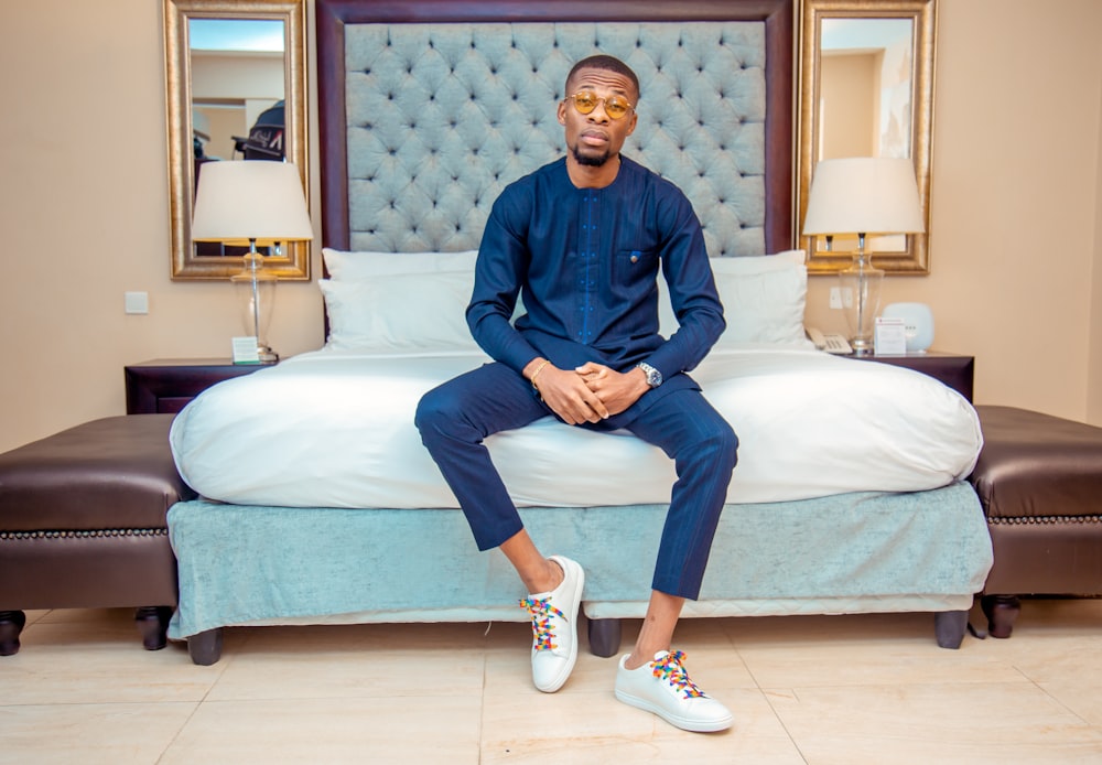 man in blue dress shirt sitting on bed