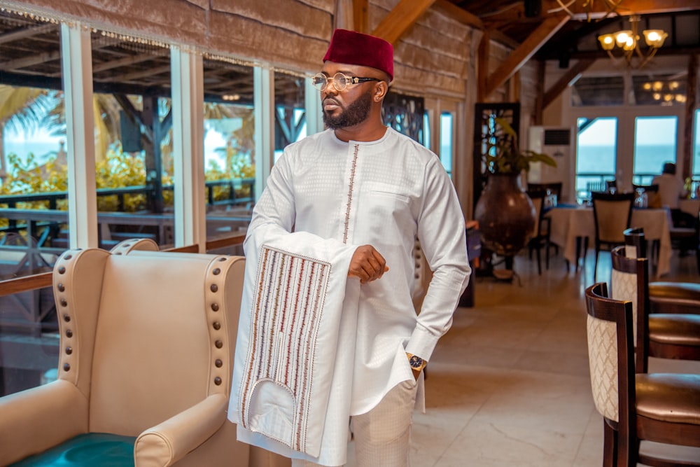 man in white long sleeve shirt and brown hat standing near brown wooden table