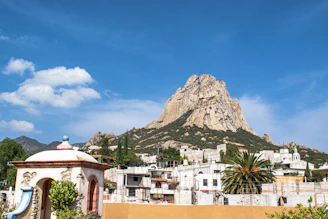 Edificios de hormigón blanco y marrón al fondo se ve Peña de Bernal, durante el día.