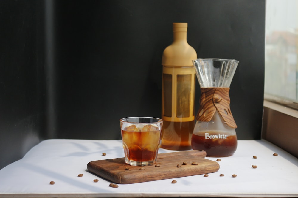 clear drinking glass beside brown bottle