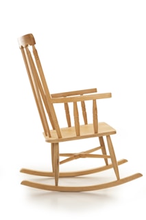 A wooden rocking chair with a high backrest and curved rockers, featuring a natural finish and classic design style.