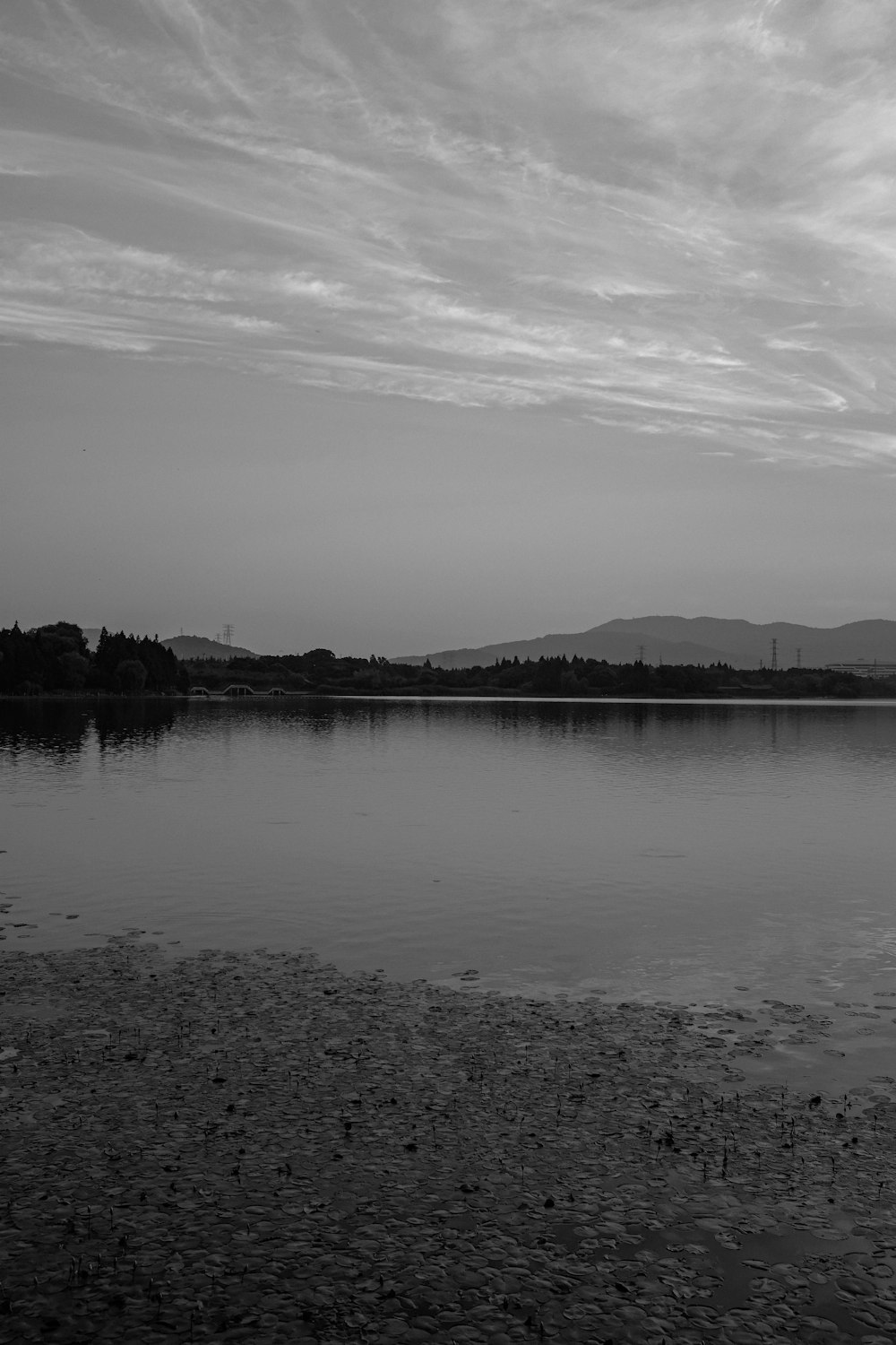 grayscale photo of body of water near mountain