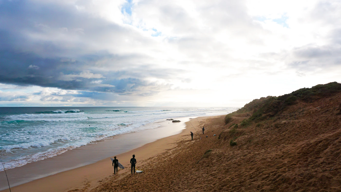 Two figures walking a wide beach at dusk