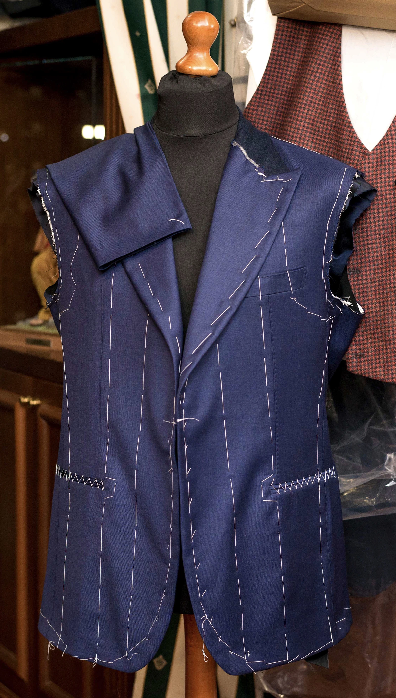 A tailored suit jacket and tie fitted on a workroom mannequin