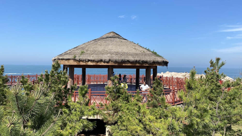 people sitting on brown wooden chairs near brown wooden house under blue sky during daytime