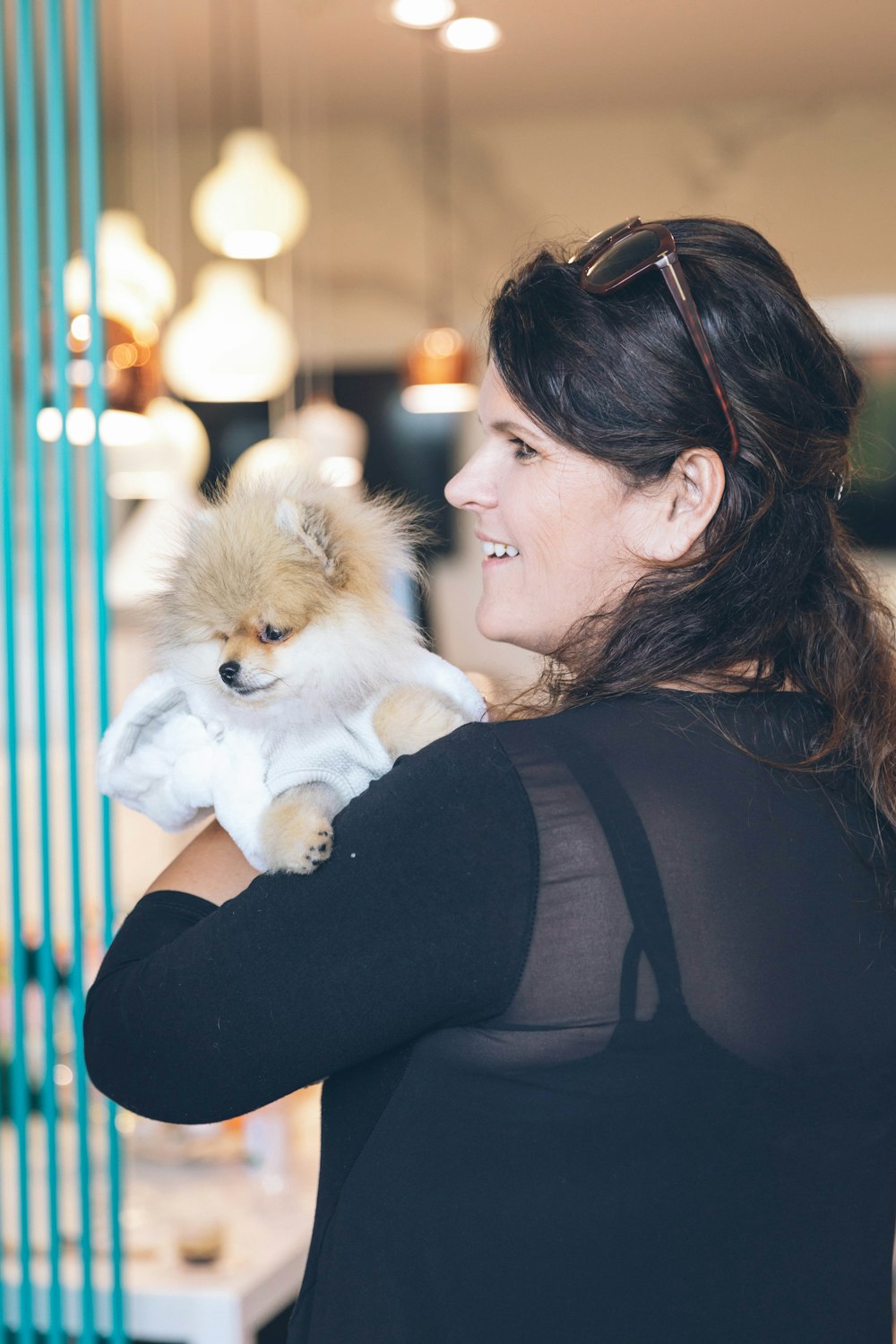 woman in black long sleeve shirt carrying brown pomeranian puppy