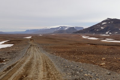 brown field near mountain under white sky during daytime gravel teams background