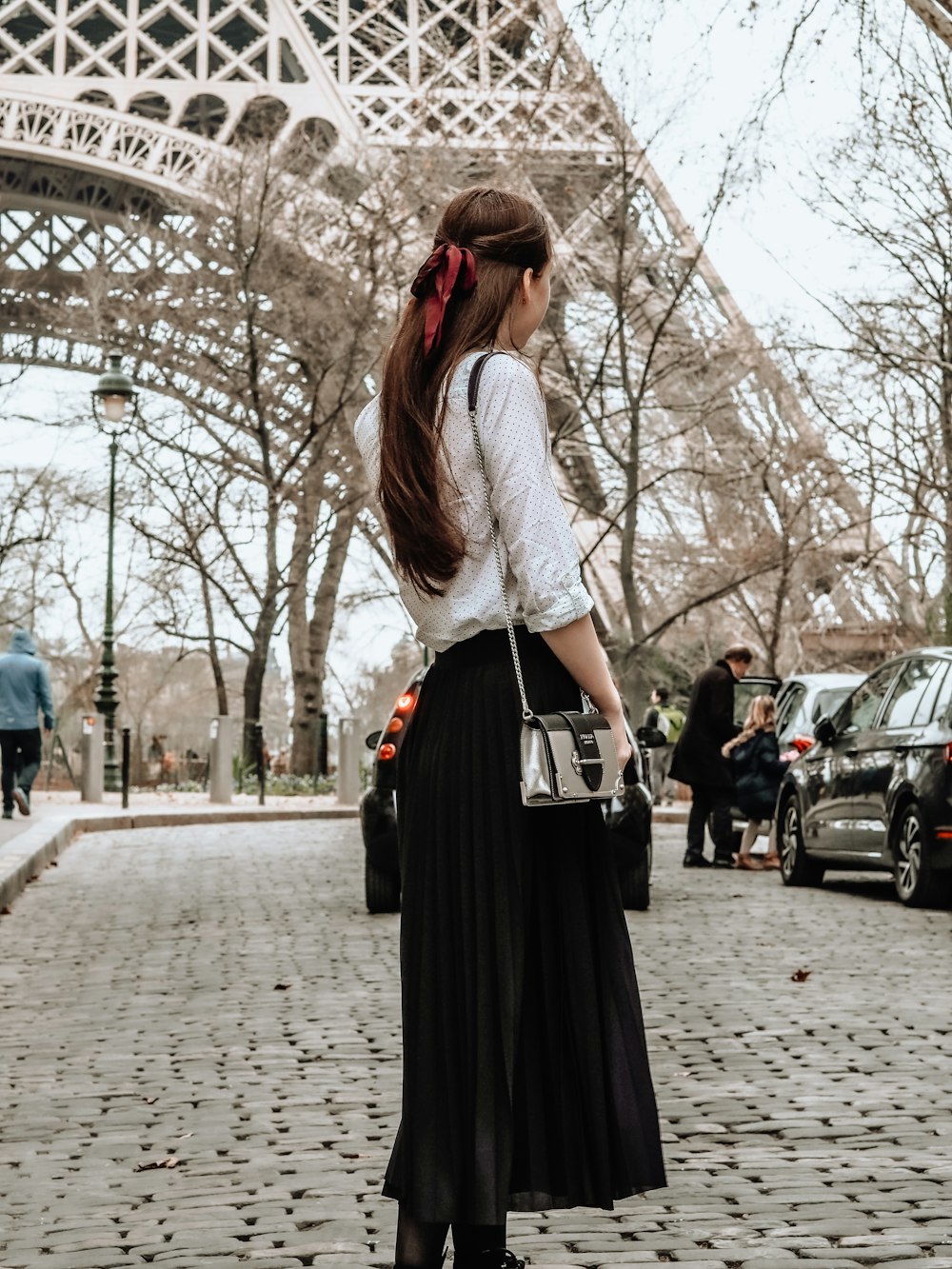 femme en robe blanche et noire debout sur le trottoir pendant la journée