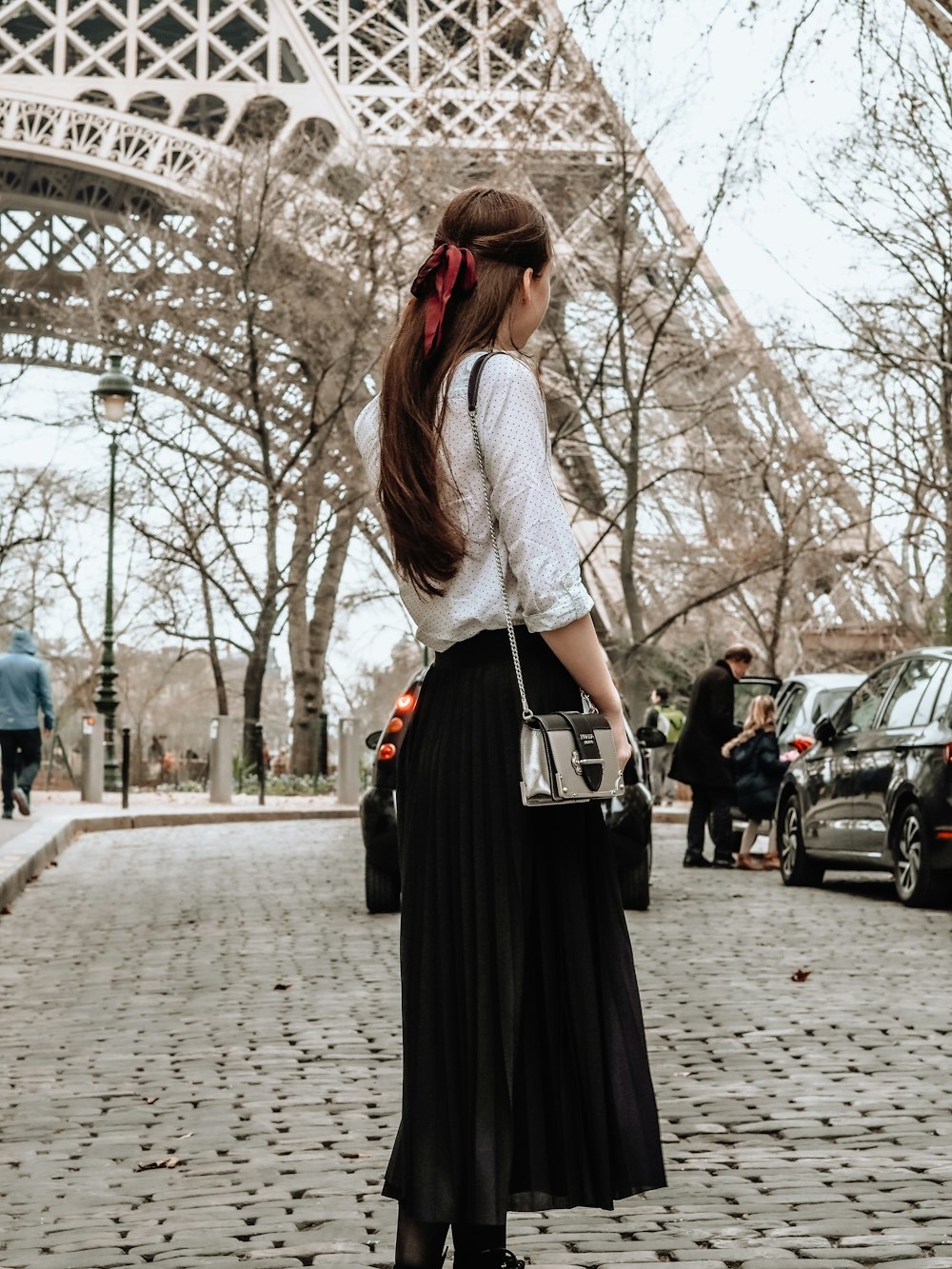 woman in white and black dress standing on sidewalk during daytime